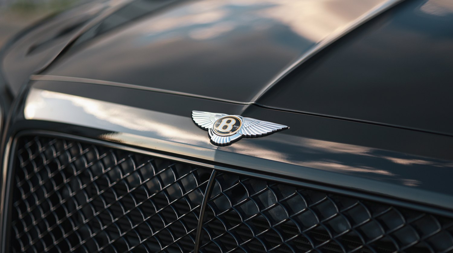 Flying B emblem on the corrected hood of a black Bentley Bentayga Speed