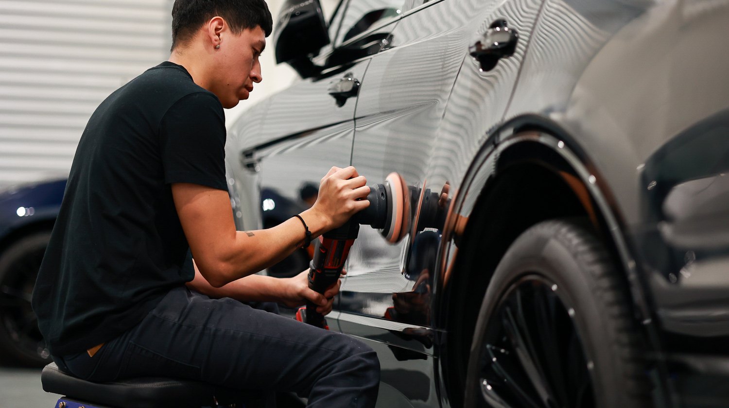 Close view of machine polishing on a black Bentley Bentayga