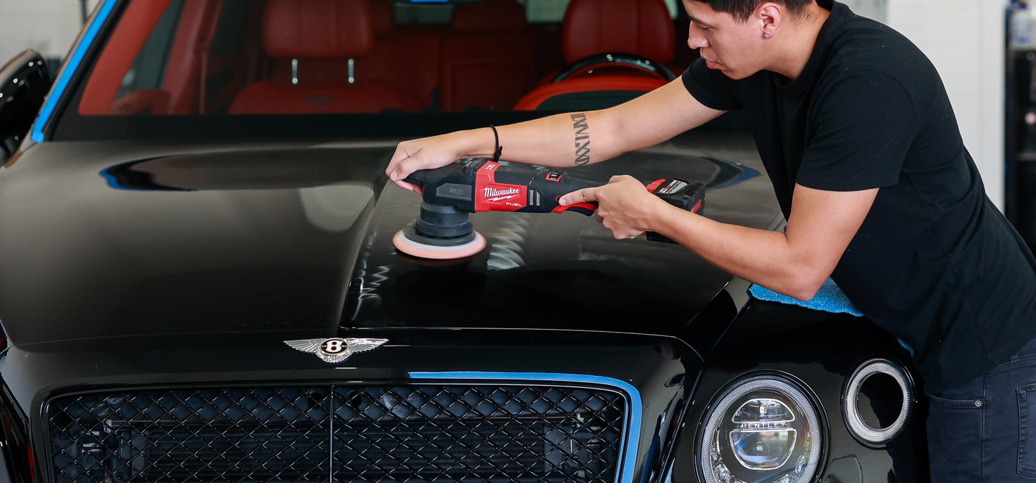 Machine polishing the hood of a black Bentley Bentayga Speed
