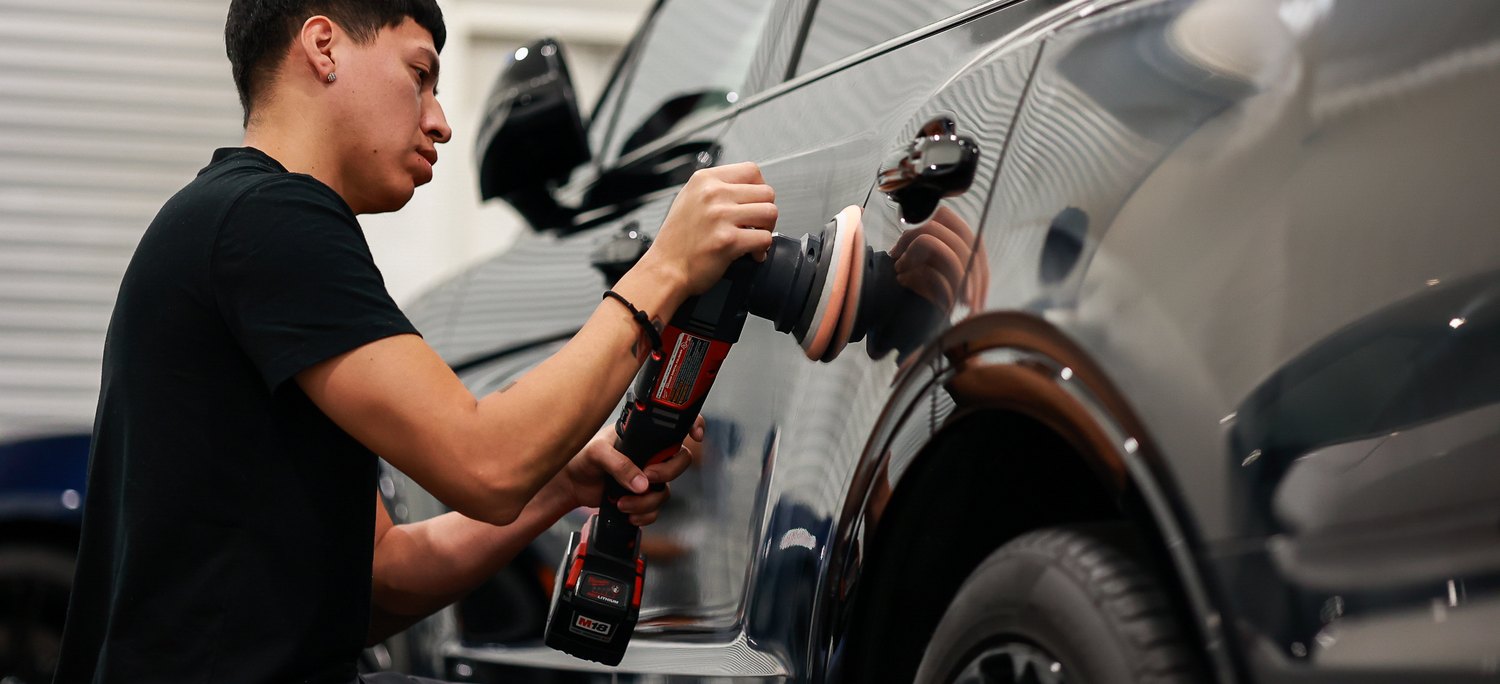 Machine polishing the rear door of a black Bentley Bentayga Speed