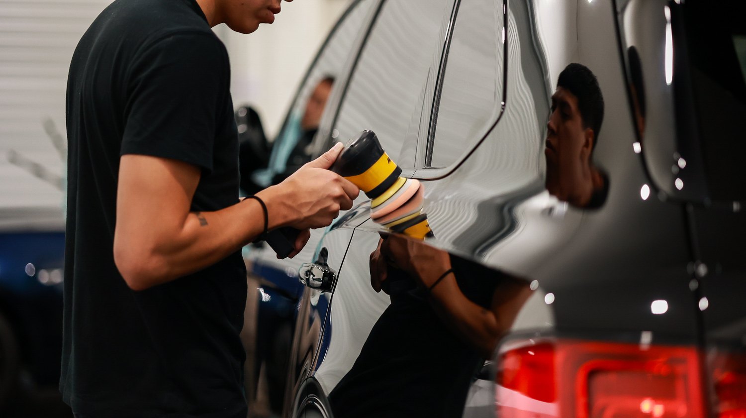 Polishing the rear quarter of a black Bentley Bentayga Speed with a small polisher