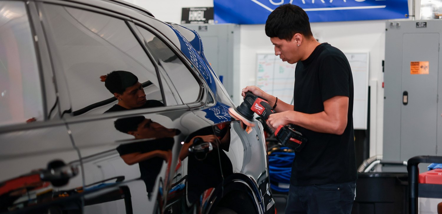 Preparing a polisher beside the rear door of a black Bentley Bentayga Speed