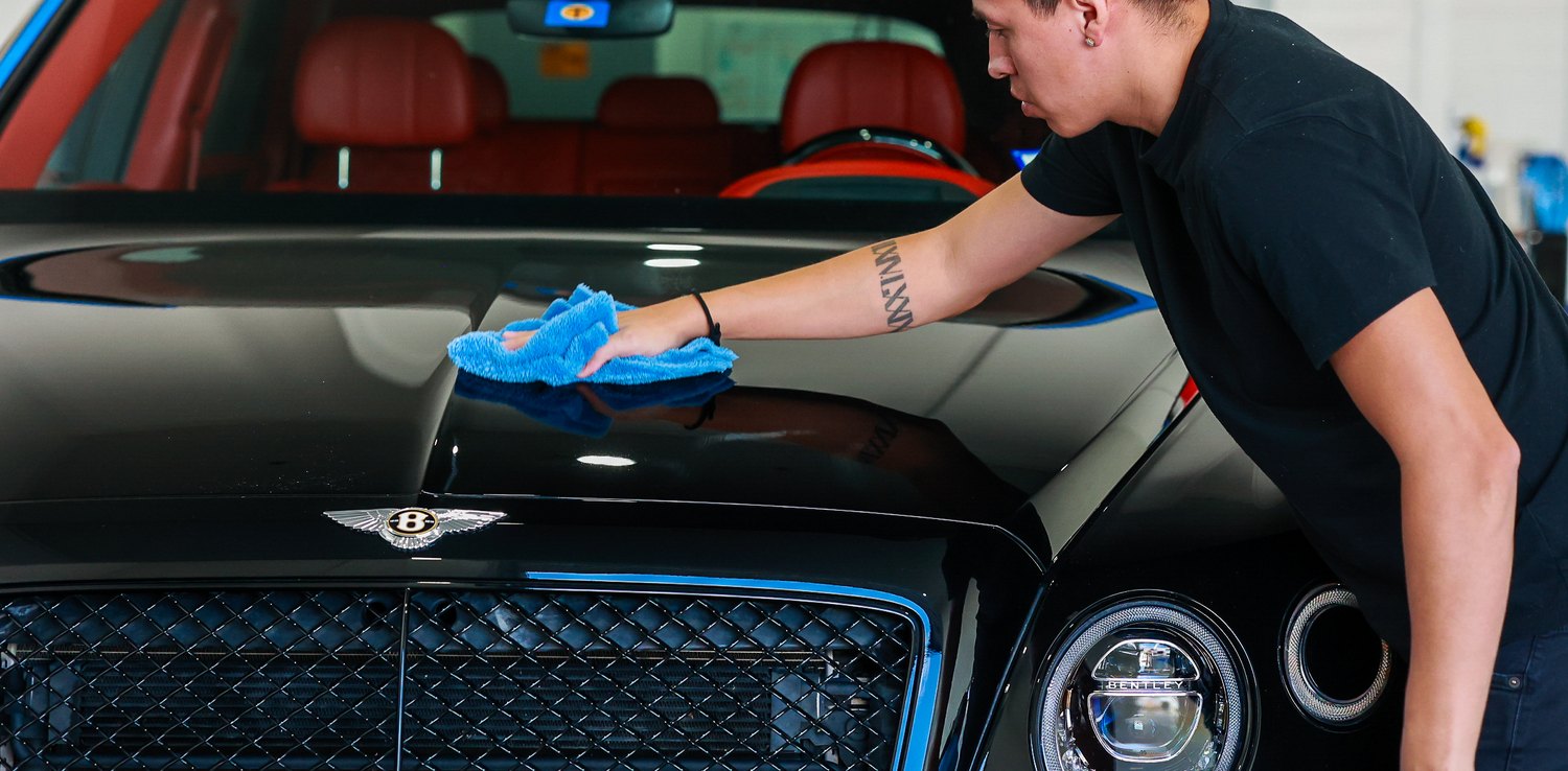 Wiping down the hood of a black Bentley Bentayga Speed