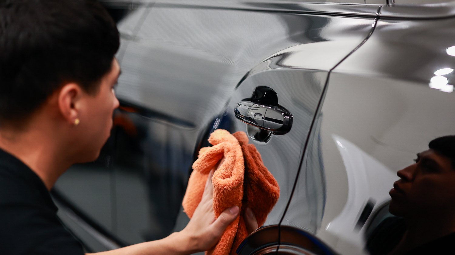 Wiping around the rear door handle of a Bentley Bentayga after polishing