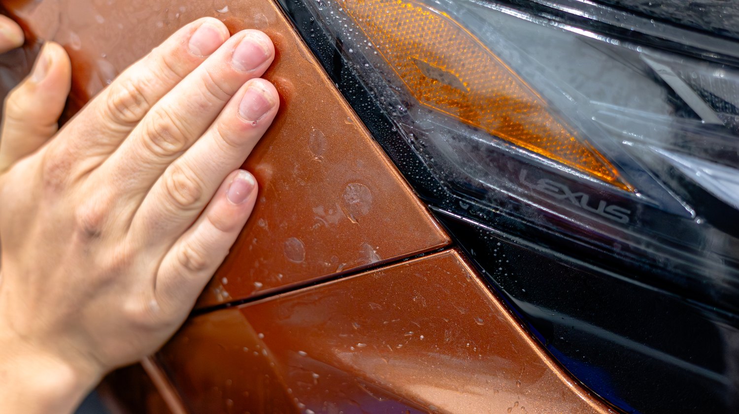 Smoothing PPF into the fender seam by the headlight of a copper Lexus RX 350