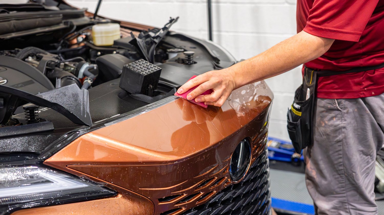 Squeegeeing PPF on the front bumper of a copper Lexus RX 350