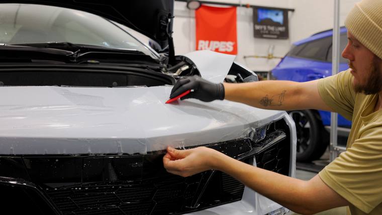 White Chevrolet Corvette C8 Z06 paint protection film — trimming front bumper edge at Humble Crew Auto Spa, Plano TX